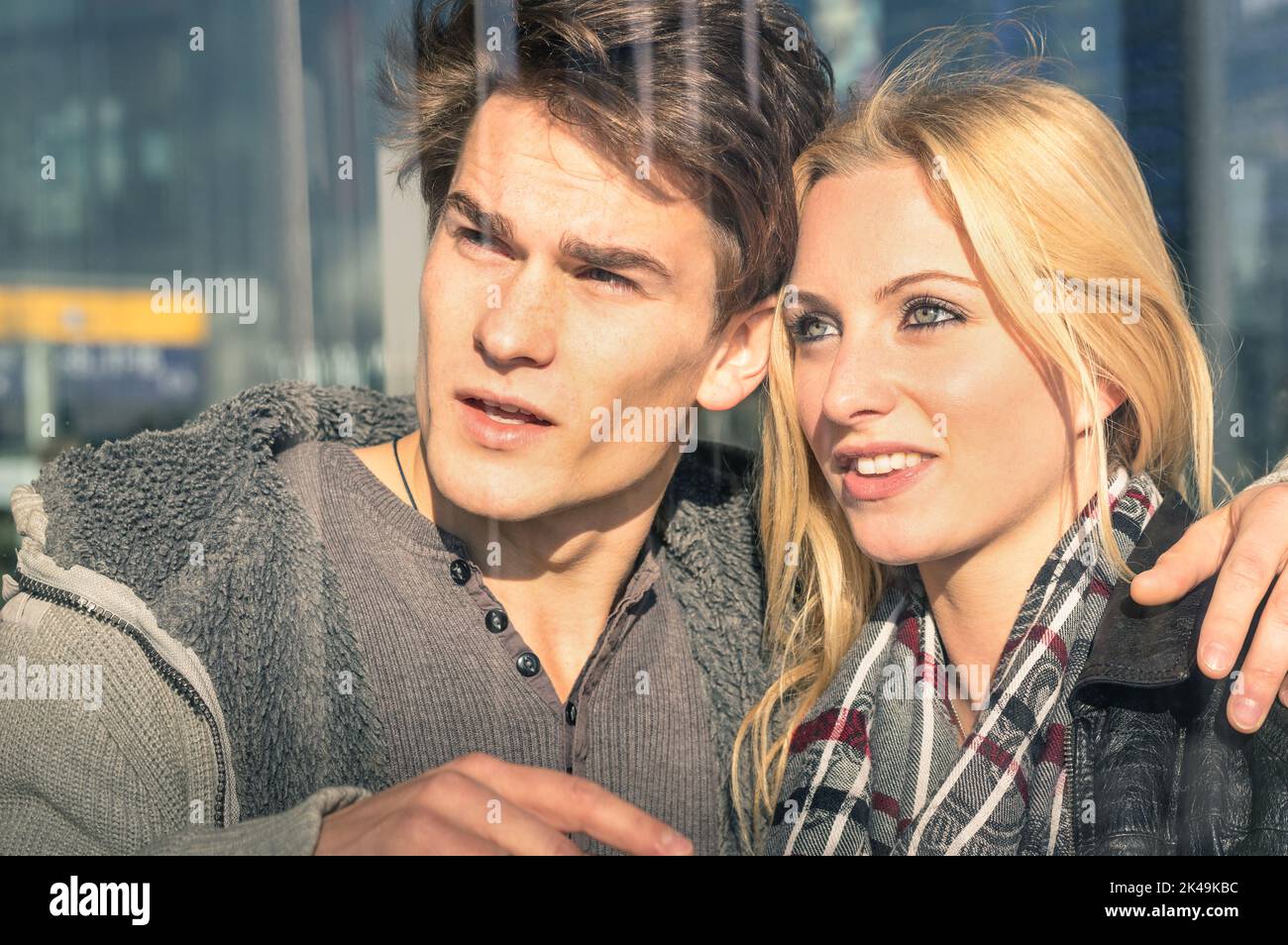 Junge Liebespaare hinter Glasreflexen - schöner Mann und schöne Frau, die etwas herumgucken - Beginn einer Liebesgeschichte über einen Jahrgang Stockfoto