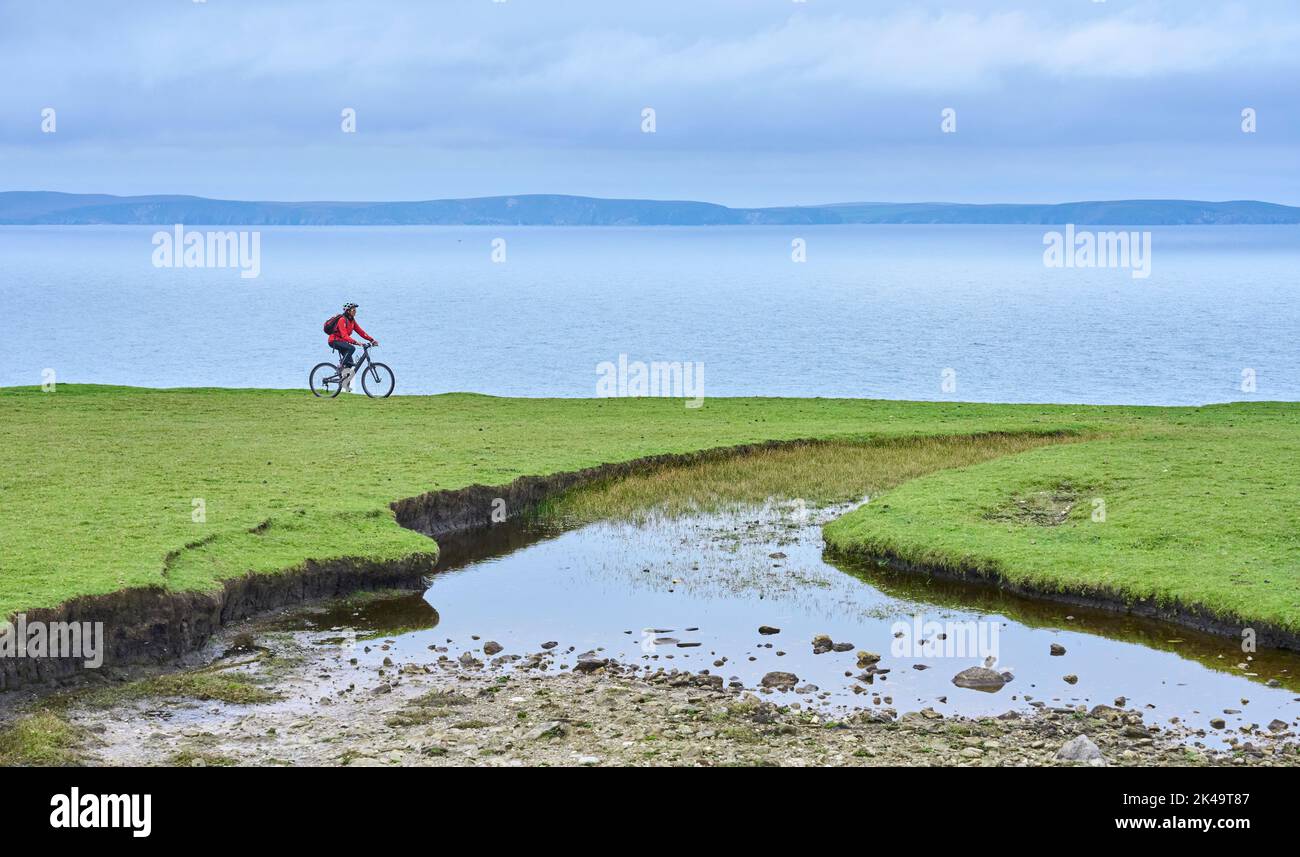 Nette ältere Frau auf dem Mountainbike, mit dem Fahrrad auf den Klippen von Cnoc an Daimh, Kilgalligan, dem nördlichen Teil der Republik Irland Stockfoto