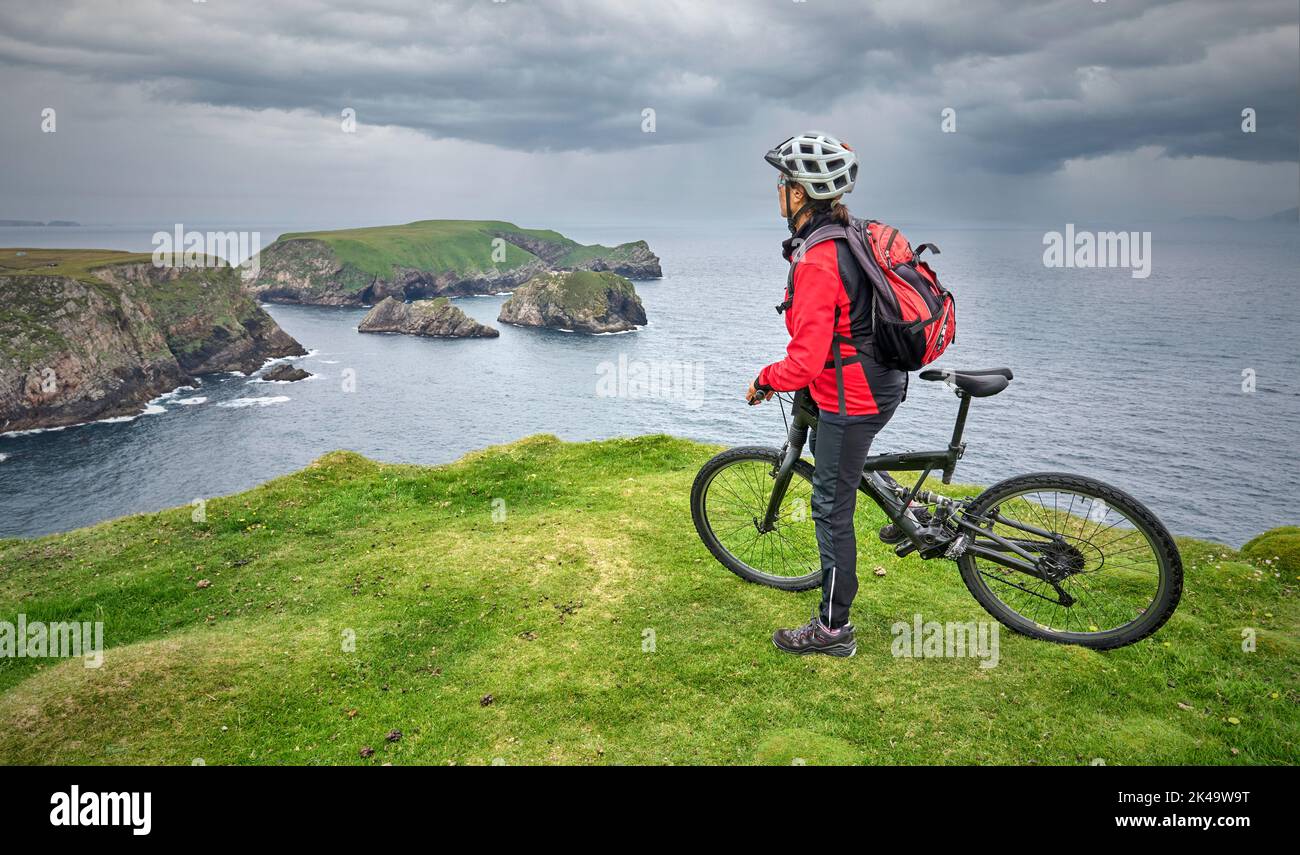 Nette ältere Frau auf dem Mountainbike, mit dem Fahrrad auf den Klippen von Cnoc an Daimh, Kilgalligan, dem nördlichen Teil der Republik Irland Stockfoto