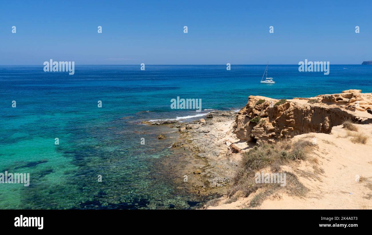 Panoramablick auf Cala Saona auf der Insel Formentera mit einem Segelboot, das in der Nähe des Strandes verankert ist. Spanien Stockfoto