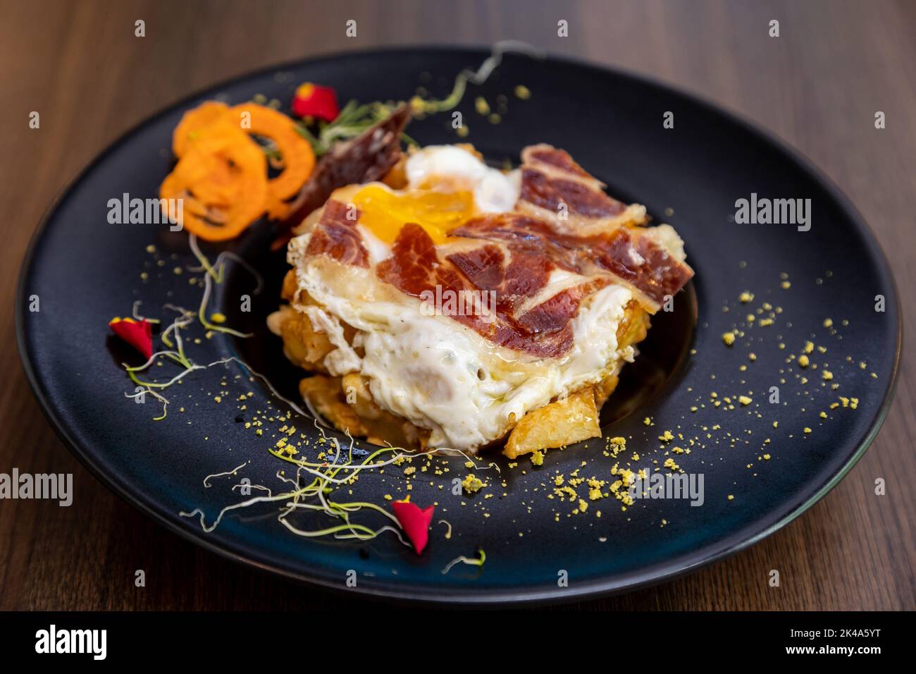 Eine Nahaufnahme von köstlichen Huevos rotos. Ein spanisches Gericht mit Spiegeleiern, Kartoffeln und Fleisch. Stockfoto