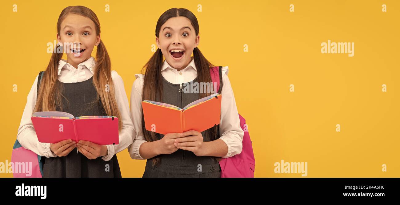 Schulmädchen Freunde. Überraschte Kinder in formellen Uniformen lesen Schulbücher gelben Hintergrund, Bibliothek. Banner der Schülerin. Schülerin Stockfoto