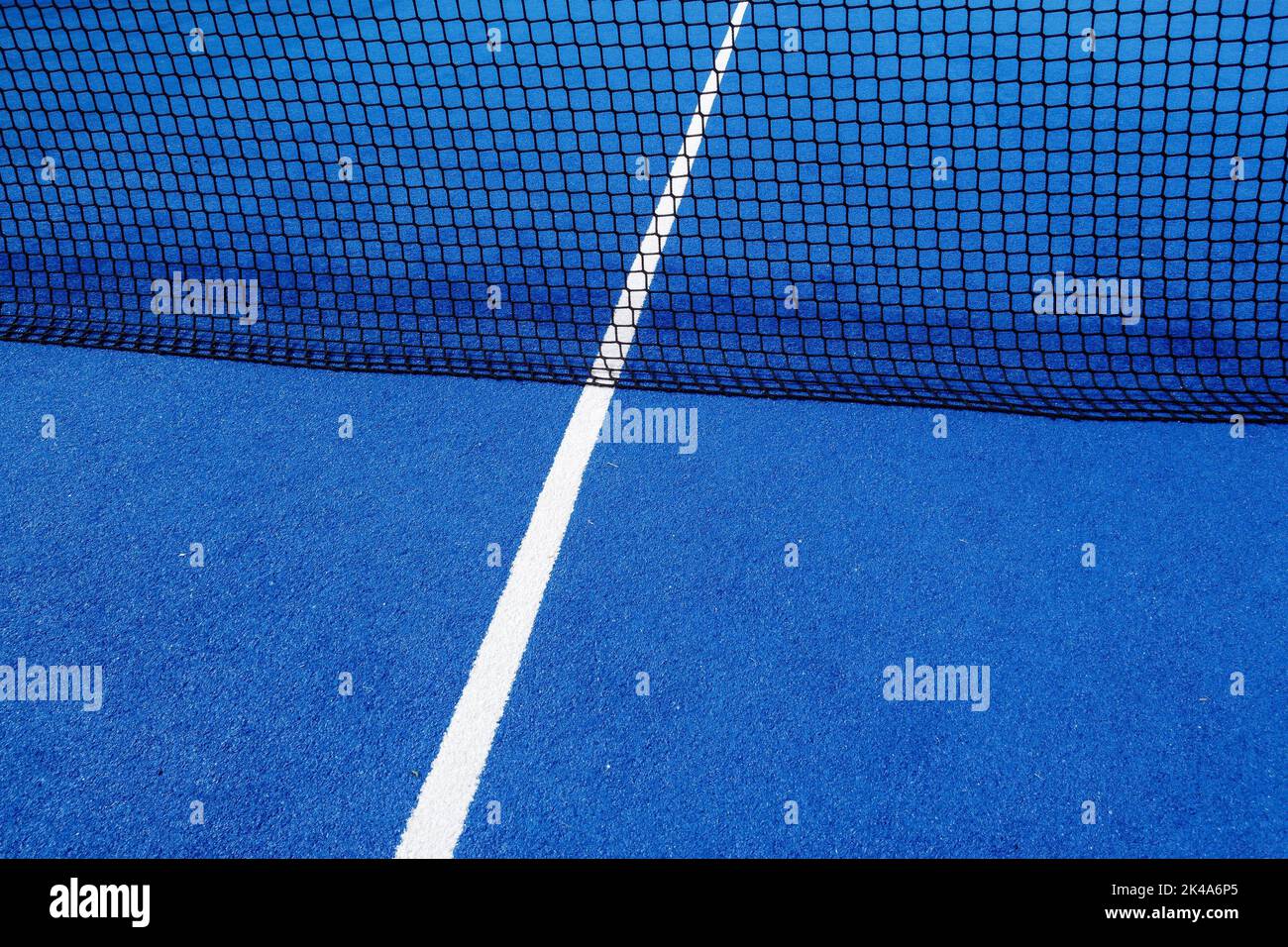 Blick auf das Netz und die Mittellinie eines blauen Paddle-Tennisplatzes. Stockfoto
