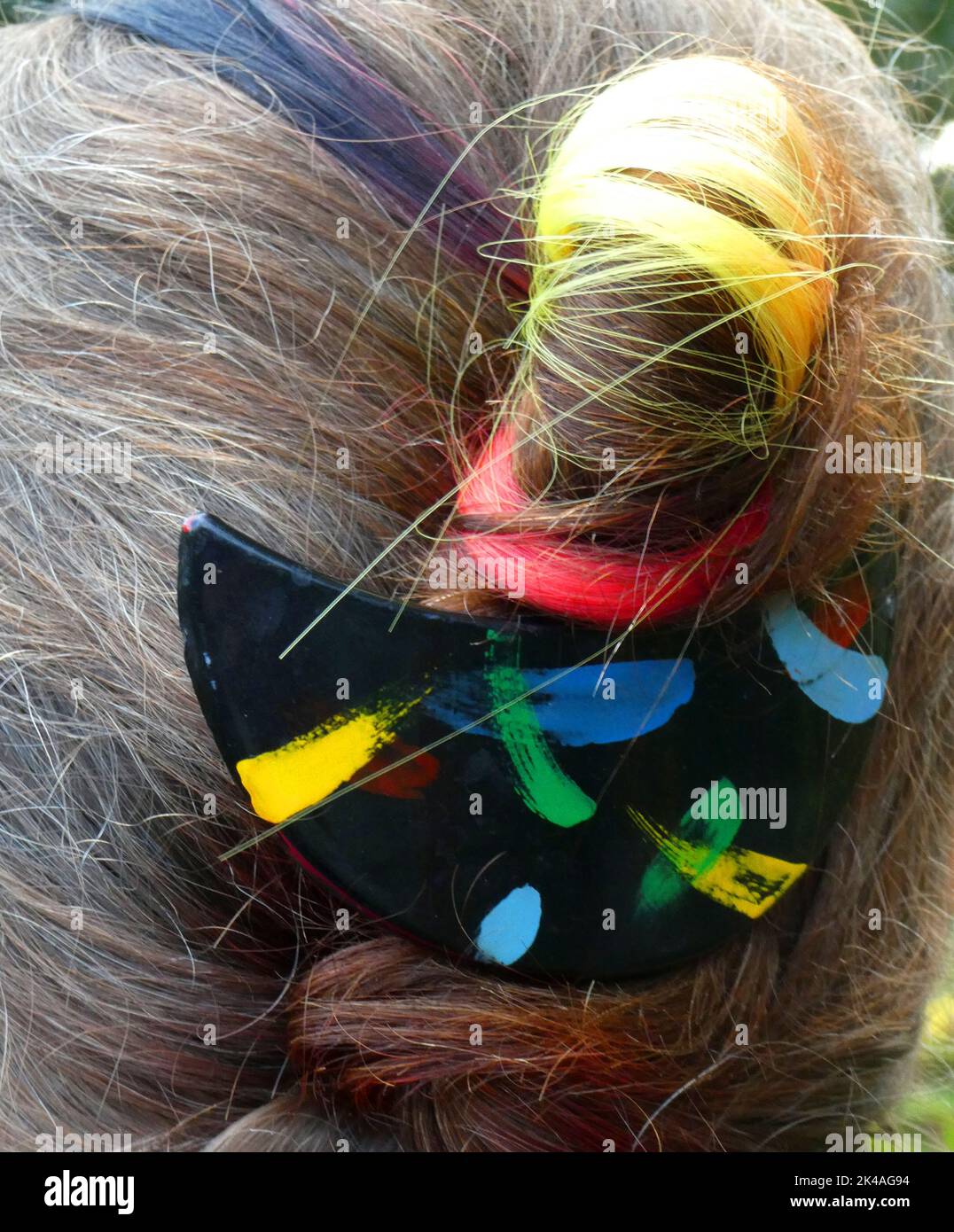 Kleine schwarze, rote, gelbe Haarverlängerung kombiniert mit einem schwarzen Haarclip Stockfoto