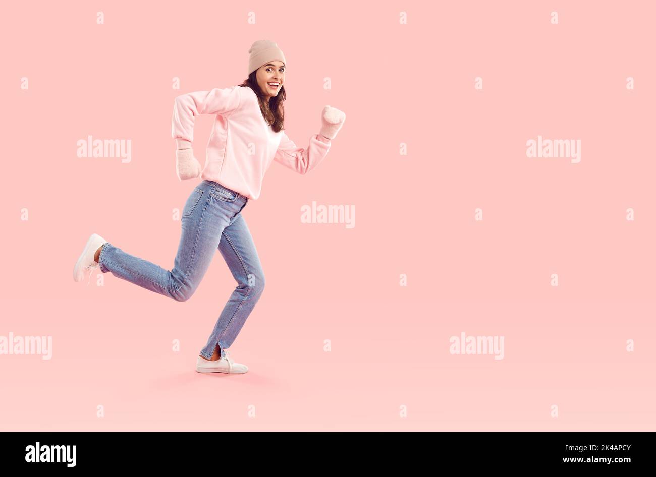 Glückliche Frau in legerer Kleidung, die sich zum Winterverkauf beeilt und auf dem Hintergrund des Kopierbereichs läuft Stockfoto