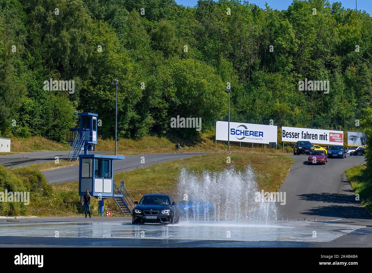 BMW m2 Sportwagen behält Kontrolle Dodges Hindernis in Form von Wasserfontänen auf rutschigem Untergrund, FSZ II Driving Safety Center, Nürburgring Rennen Stockfoto
