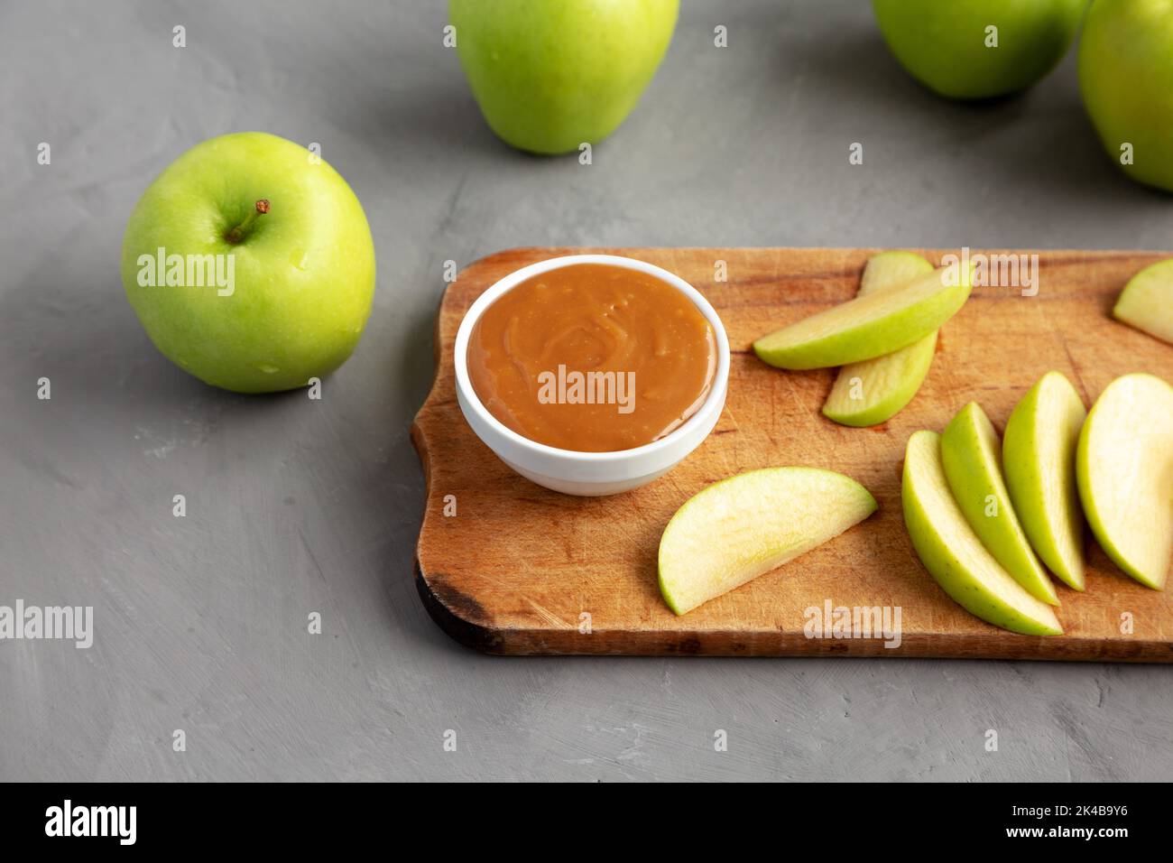 Hausgemachter Karamell-Apfel-Dip auf einem rustikalen Holzbrett, Seitenansicht. Stockfoto