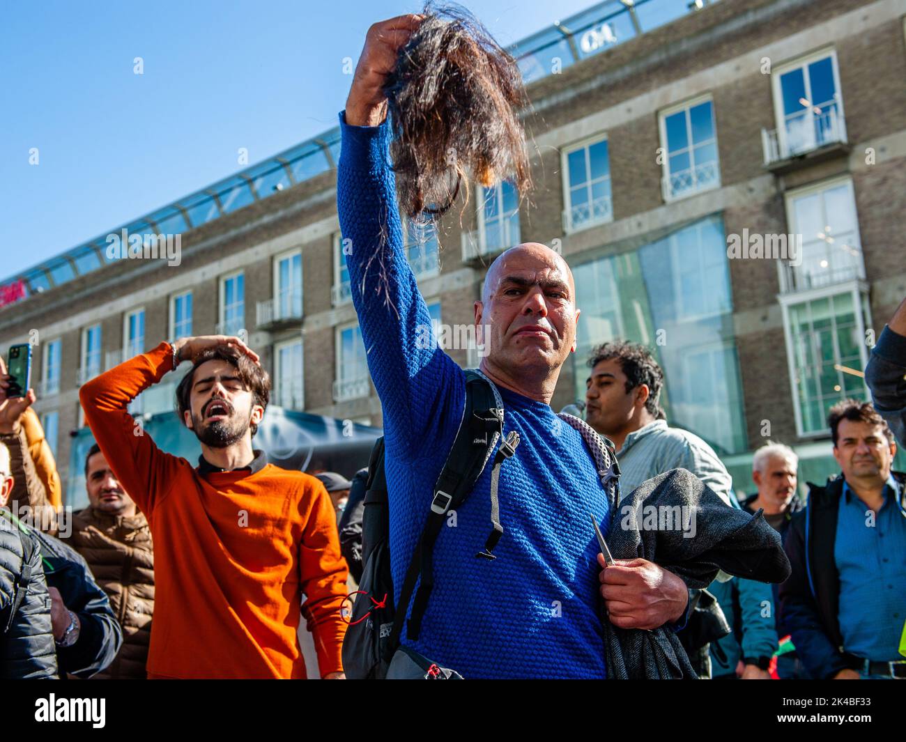 Während der Demonstration wird ein iranischer Mann mit geschnittenen Haaren der iranischen Frauen gesehen. Nach zweiwöchigen Kundgebungen, die durch den Tod von Mahsa Amini ausgelöst wurden, haben Menschen im Iran und im Ausland am Samstag weltweite Proteste gegen die Islamische Republik geplant. Hunderte von Iranern versammelten sich im Zentrum der niederländischen Stadt Eindhoven, um die Stimme des iranischen Volkes zu erheben und Gerechtigkeit für die systematischen Verbrechen und Gewalt zu fordern, die von den Behörden des islamischen Regimes gegen die Iraner begangen wurden. Mehrere iranische Frauen und ein Mann schnitten sich in der Öffentlichkeit als ergreifende Form von die Haare ab Stockfoto