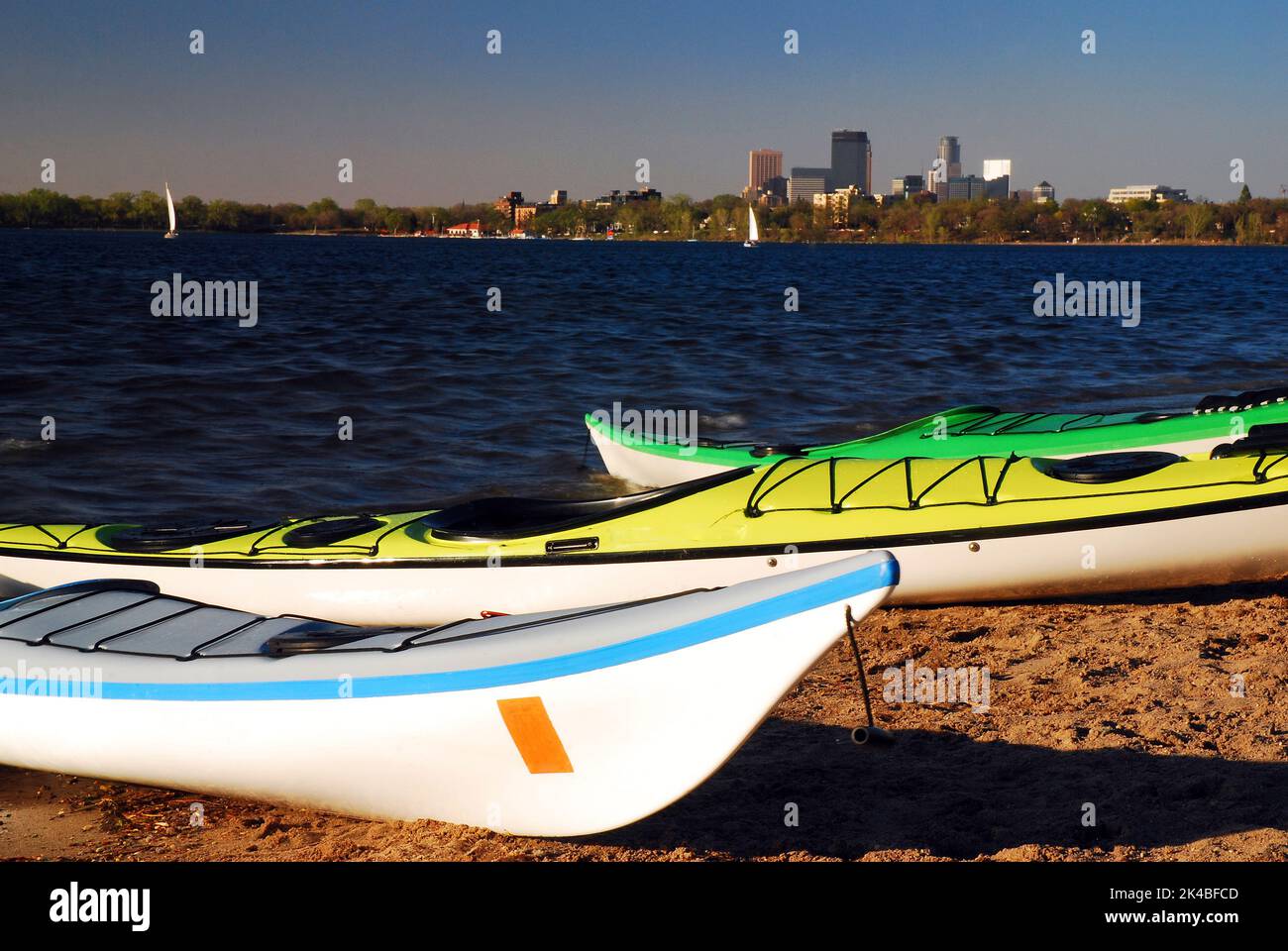 Kajaks erwarten Sie auf dem Lake Calhoun mit der Minneapolis Skyline, die an einem sonnigen Sommerferientag hinter dem Wasser aufsteigt Stockfoto