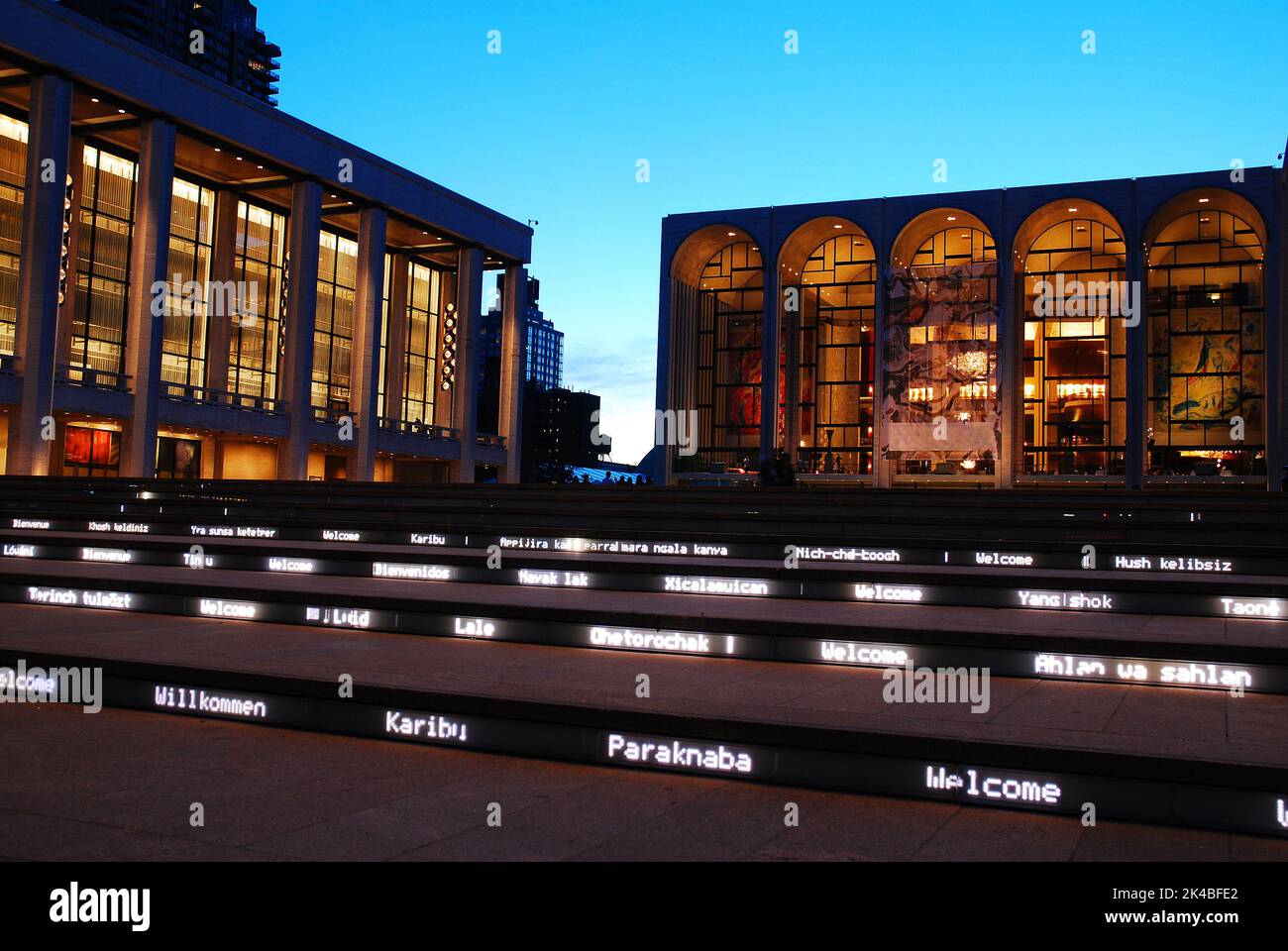 Die Stufen des Lincoln Center Performing Arts Center in New York City begrüßen Gäste in der Nacht mit beleuchteten Grüßen in Fremdsprachen Stockfoto
