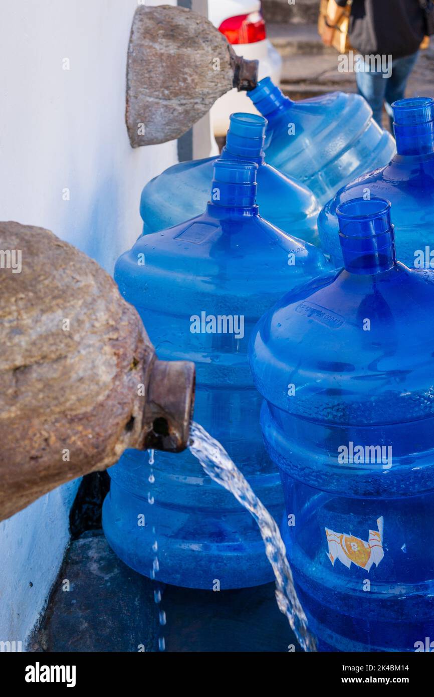 Blaue Wassergallonen mit Wasser am Brunnen Chafariz do Kaquende in Sabará, Minas Gerais, Brasilien. Stockfoto