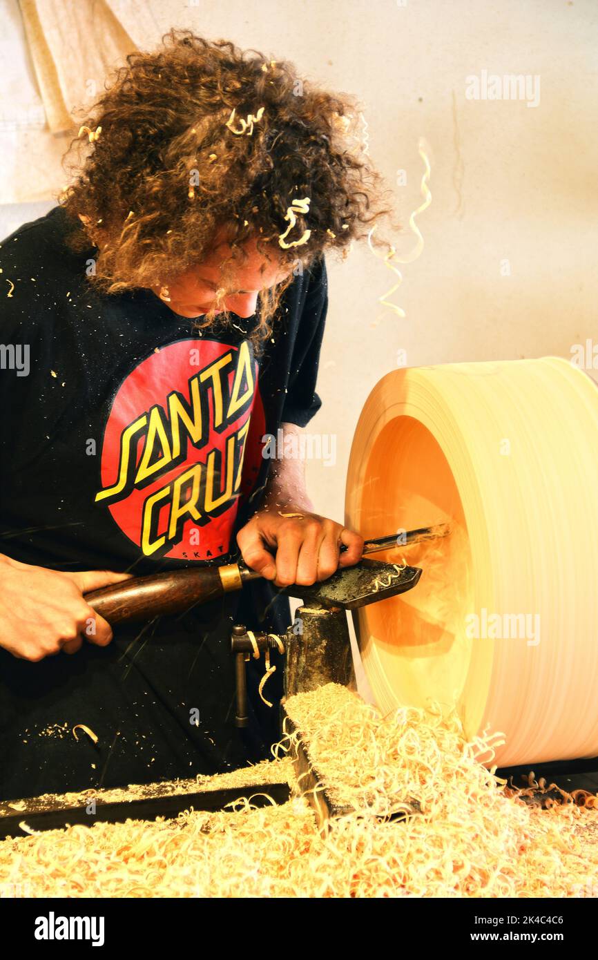 Handwerk in Österreich bearbeitet der junge Mann ein Stück Holz auf sehr traditionelle Weise Stockfoto