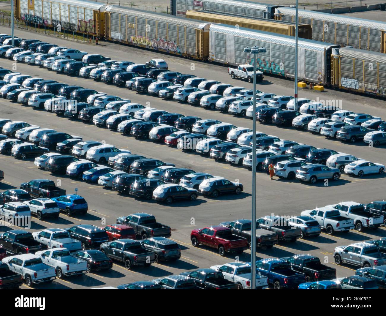 Eine Luftaufnahme eines Autoverteilungs- und Zulassungszentrums, das sich an einem sonnigen Tag neben Güterzugwagen befindet. Stockfoto