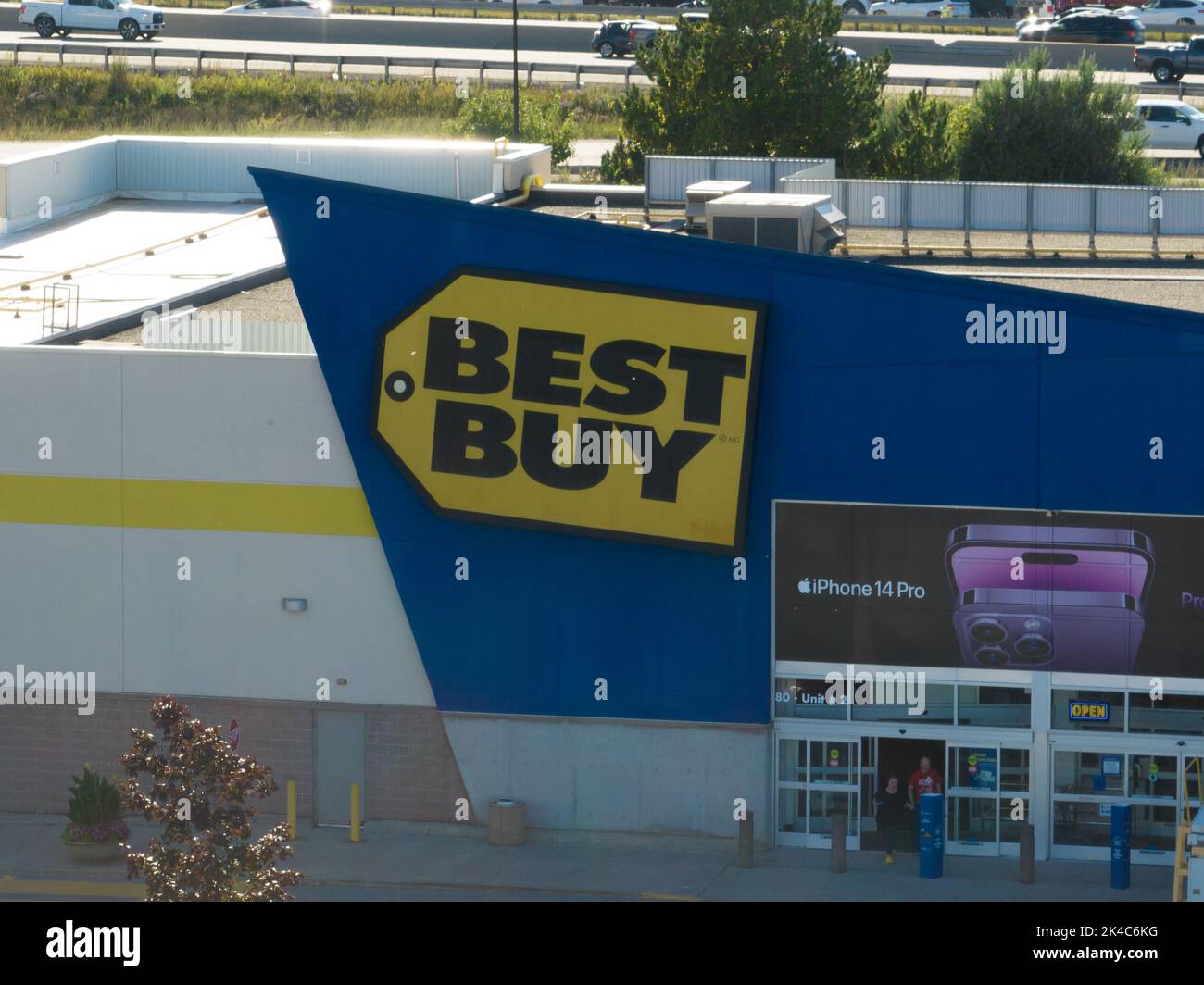 Ein Blick aus der Vogelperspektive auf die Vorderseite eines Best Buy-Einzelhandelsgeschäfts an einem sonnigen Tag; ein Werbespot für das neueste iPhone 14 Pro auf der Vorderseite des Geschäfts Stockfoto