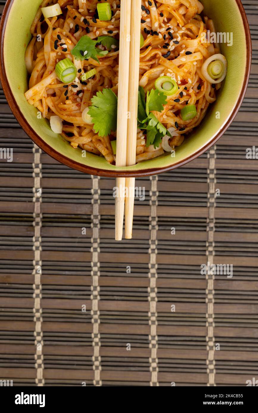 Blick von oben Nahaufnahme von asiatischen Wok-Rührnudeln mit Essstäbchen auf der Matte Stockfoto