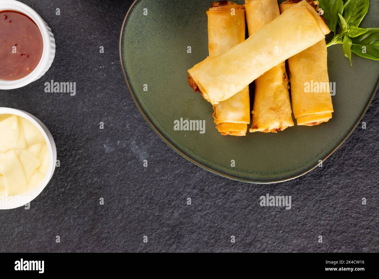 Ansicht von oben der asiatischen Frühlingsrollen auf grauem Teller und Gewürzen auf grauem Hintergrund Stockfoto