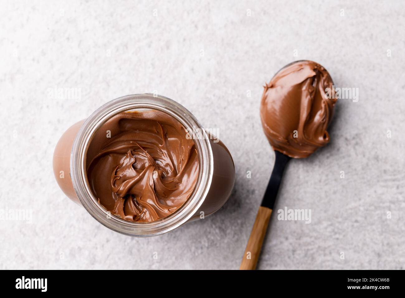 Bild von Löffel und Glas mit Schokoladencreme auf hellgrauem Hintergrund Stockfoto