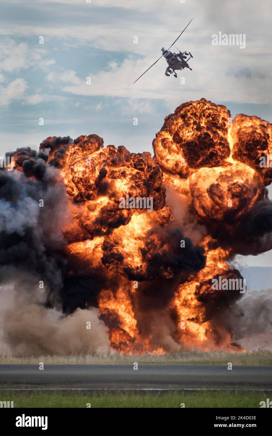 Eine vertikale Aufnahme eines Angriffshubschraubers, der über einer Explosion fliegt Stockfoto
