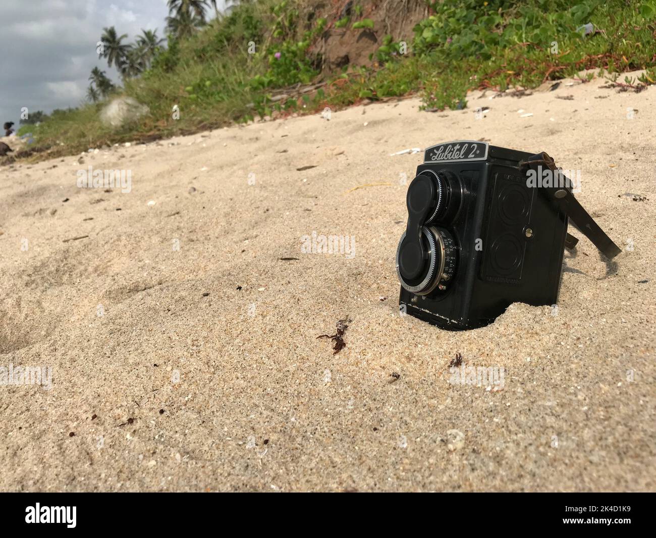 Nahaufnahme einer schwarzen Lubitel 2-Kamera, die im braunen Sand eines Strandes in Cape Coast, Ghana, platziert wurde Stockfoto