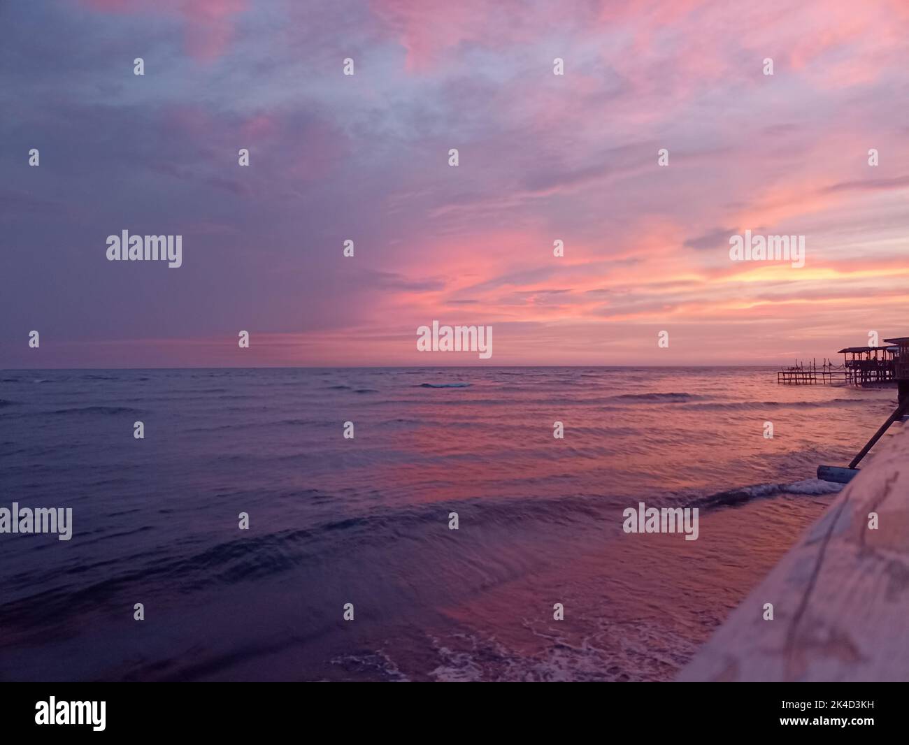 Ein herrlicher rosafarbener Sonnenaufgang in Ada Bojana, Montenegro, mit einem hellen, bewölkten Himmel über den niedrigen Gezeiten Stockfoto