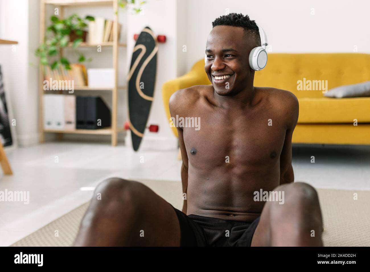 Glücklicher junger afrikanischer Mann, der sich nach einer individuellen Ausbildung zu Hause entspannt Stockfoto