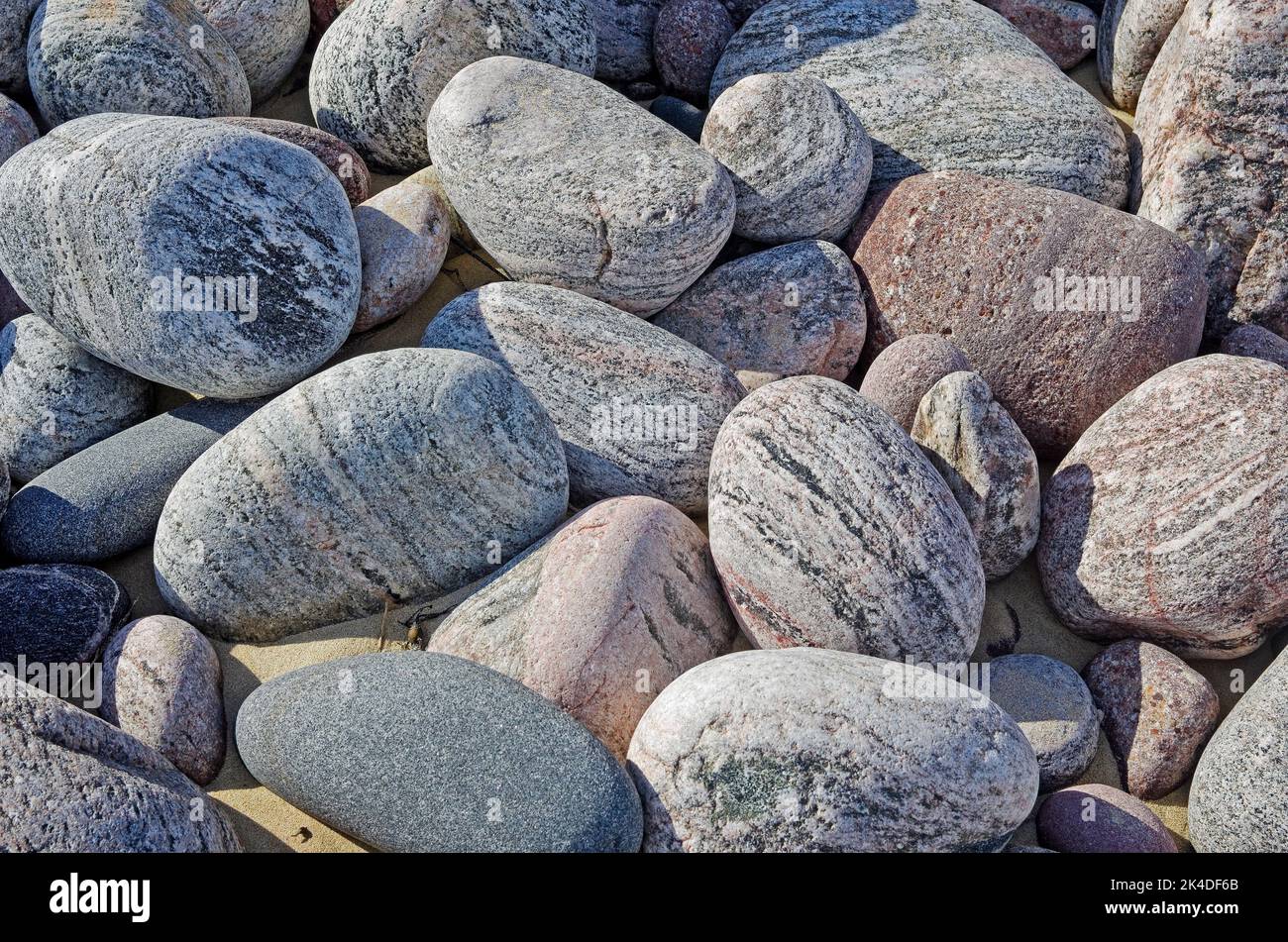 Wunderschöne, strukturierte, farbige Felsen und große Steine, die am Strand von Oldshoremore, Sutherland, Scottish Highlands, Schottland, Großbritannien, abgelagert wurden Stockfoto