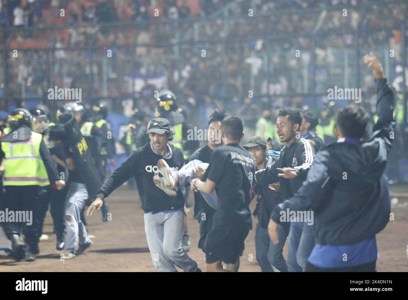 Malang, Indonesien. 1. Oktober 2022. Am 1. Oktober 2022 überführen Menschen einen verletzten Mann im Kanjuruhan-Stadion in Malang in der Provinz Ost-Java, Indonesien. Laut dem stellvertretenden Gouverneur der Provinz Emil Dardak hat die Zahl der Todesopfer bei einem Fußballspiel in der indonesischen Provinz Ost-Java am Sonntagnachmittag bei 174 gelegen. Die Tragödie ereignete sich am Samstagabend im Kanjuruhan-Stadion in Malang in der indonesischen Provinz Ost-Java, direkt nachdem der Verein Arema Malang bei einem Fußballspiel der indonesischen Liga gegen Persebaya Surabaya verloren hatte. Quelle: Xinhua/Alamy Live News Stockfoto