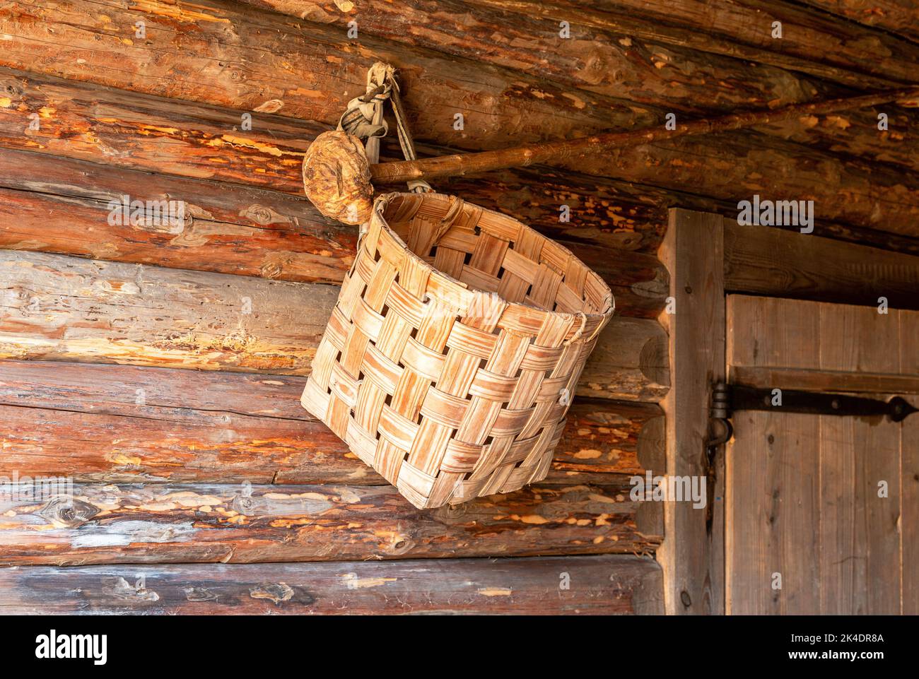 Handgemachter Korbkorb, der an der Wand eines Holzhauses hängt Stockfoto