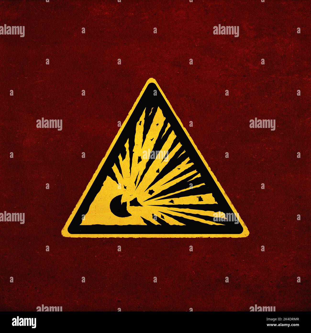 Explosives Warnschild, gelb auf grau. Symbol für Explosionsgefahr (Dreieck). Grunge-Textur-Effekt. Gelb auf rot Stockfoto