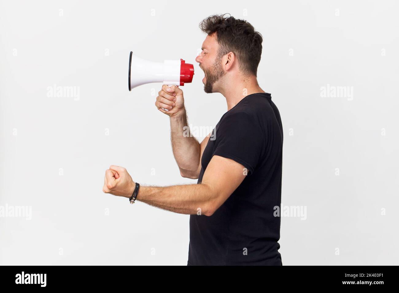 Junger Mann, der ein auf Weiß isoliertes Megaphon verwendet Stockfoto