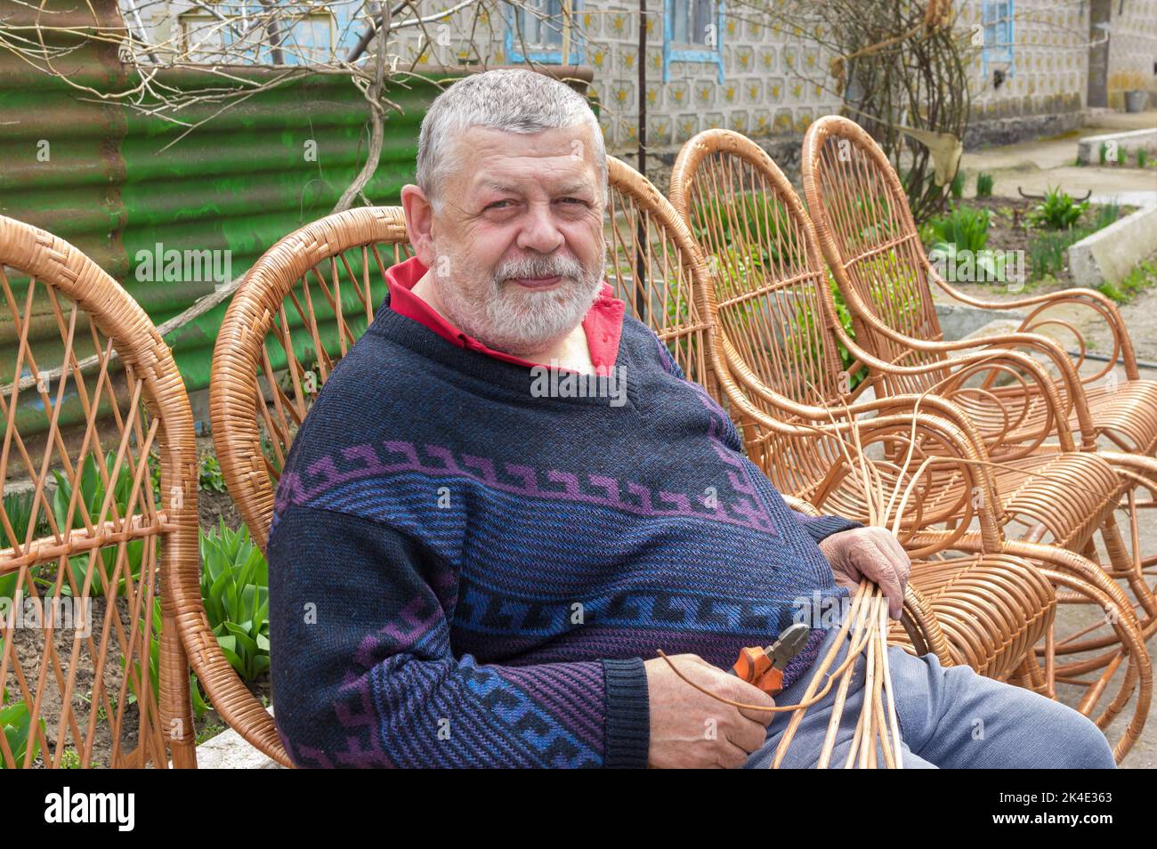 Schönes Porträt eines ukrainischen Mannes, der in einem Schaukelstuhl sitzt, den er mit Withe gemacht hat Stockfoto