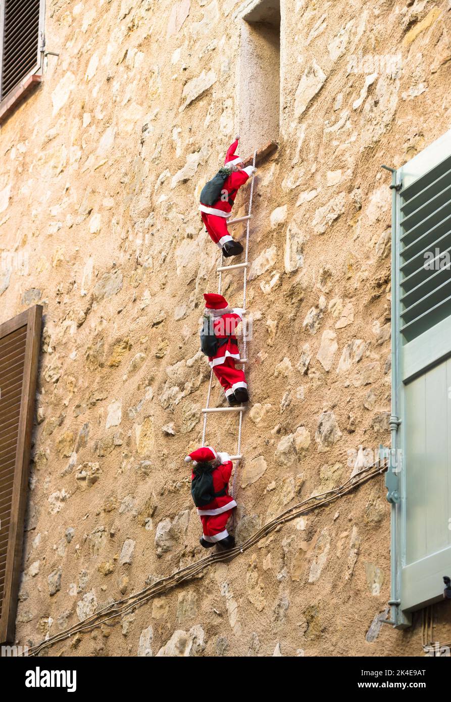 Drei Santa Claus klettern die Seilleiter an einer Fassade Stockfoto
