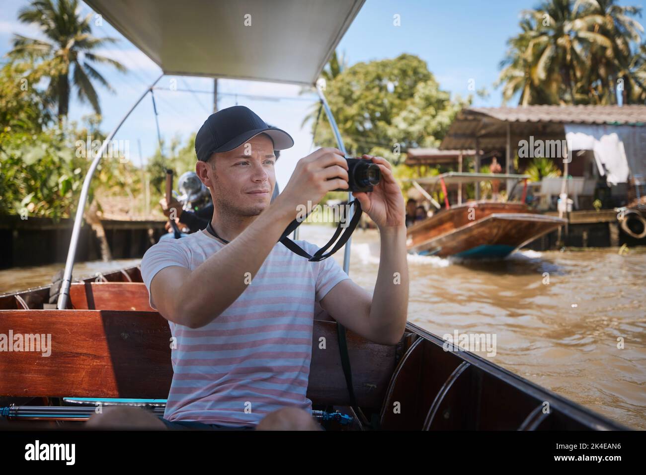 Mann, der Fotos von der Bootsfahrt zum schwimmenden Markt in der Nähe von Bangkok gemacht hat. Alleinreisende in Thailand. Stockfoto