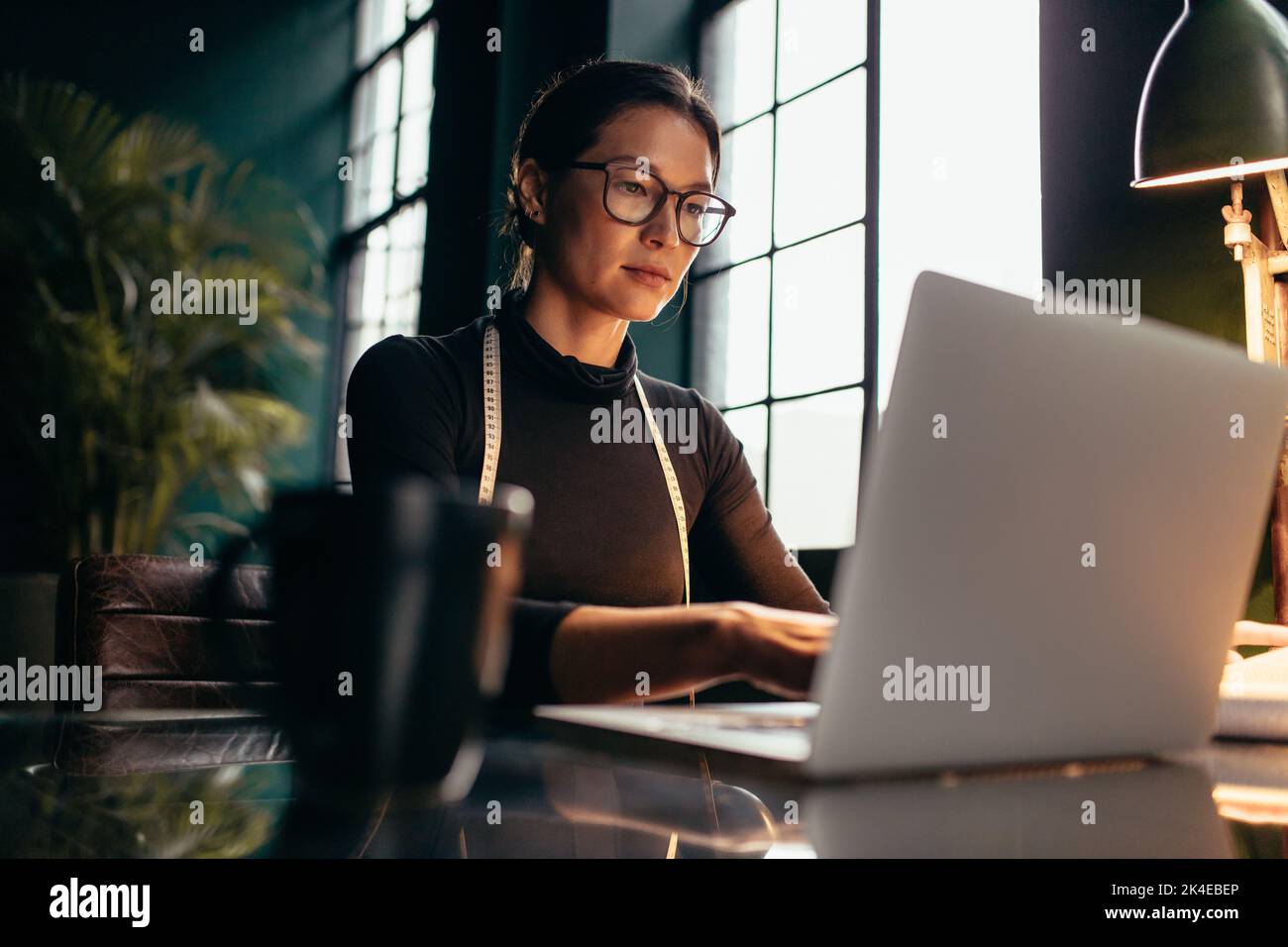 Modedesignerin, die im Studio am Laptop arbeitet. Asiatische Frau kreative Profi mit Laptop im Büro. Stockfoto