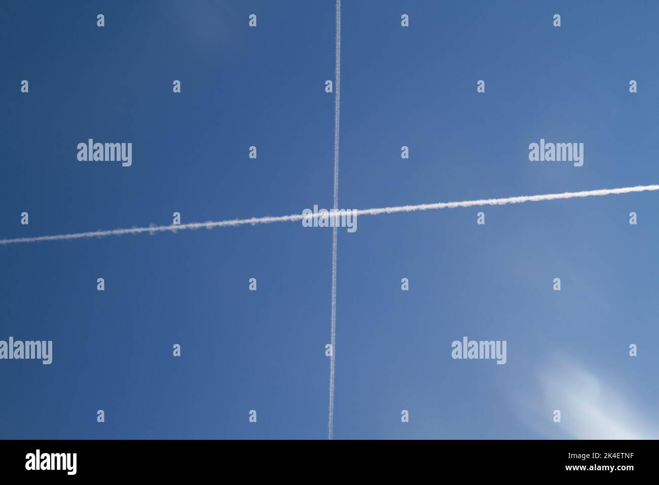 Zwei Kondensstreifen, Kondensstreifen oder Dampfspuren in einem blauen Himmel, die ein Kreuz am Himmel bilden Stockfoto