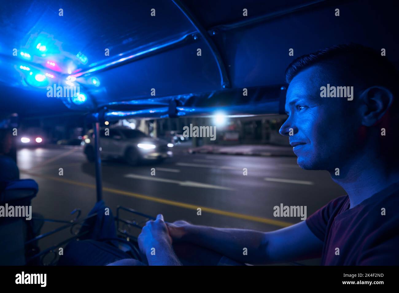 Mann genießt Tuk Tuk Fahrt in der Nacht. Porträt des Touristen im Taxi. Bangkok, Thailand Stockfoto