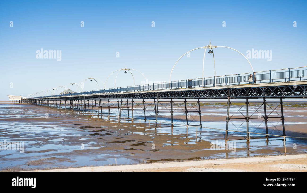 Southport Pier reflektiert sich in Wasserbecken, die bei Flut im Oktober 2022 an der Küste von Sefton zurückgelassen wurden. Stockfoto