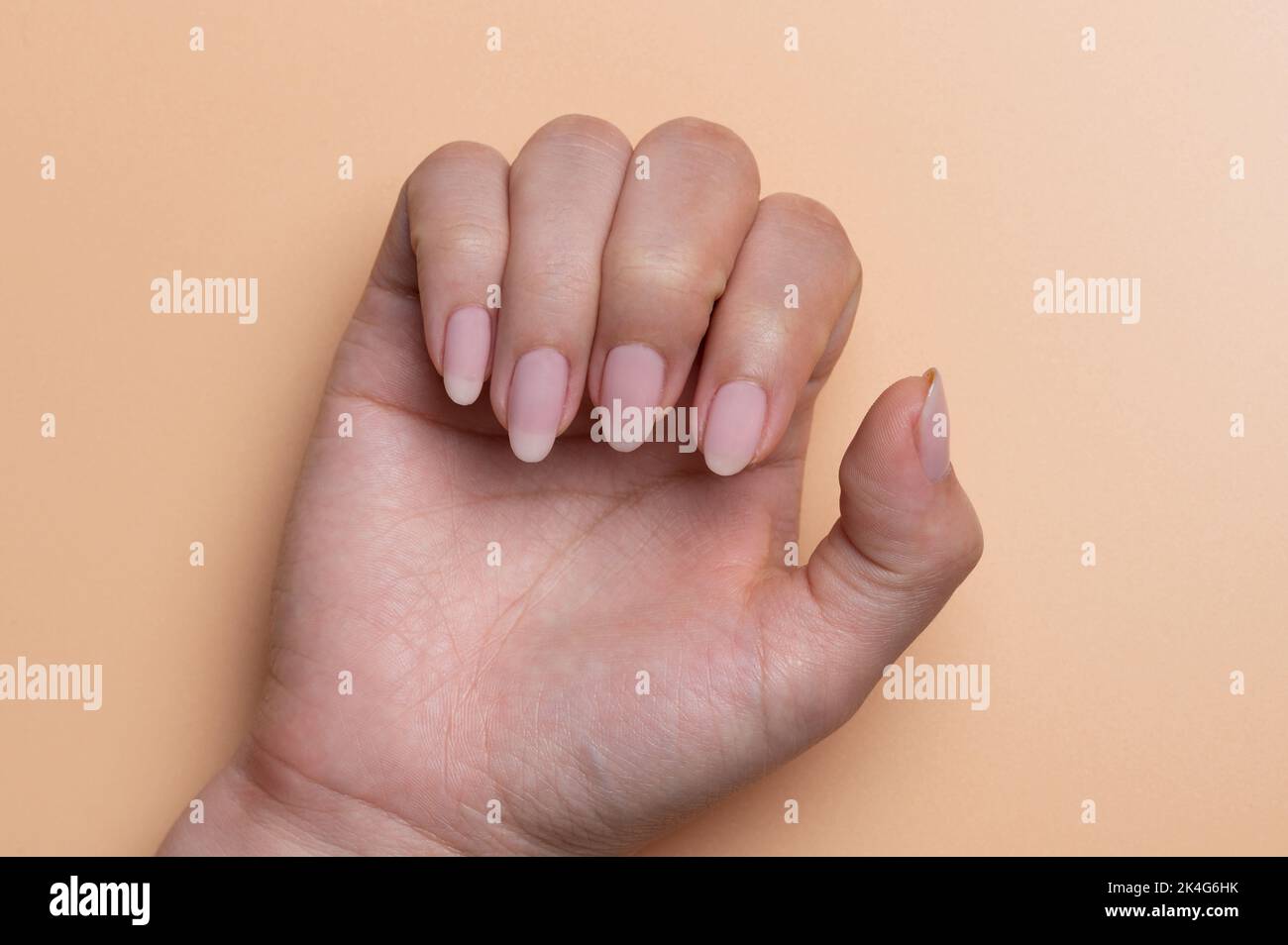 Nette hübsche Nägel auf Frau Hand Makro Nahaufnahme in beigefarbener Hintergrund Stockfoto