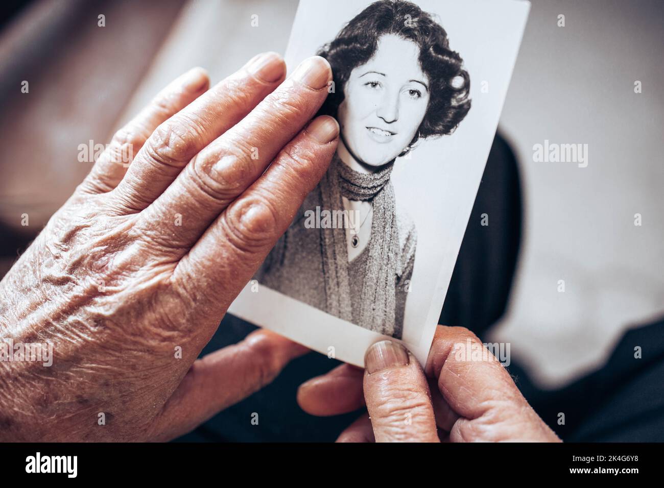 UM 1970: Hände einer älteren Frau mit einem Vintage-Schwarz-Weiß-Foto der jungen Frau. Konzept des Zeitvergehens Stockfoto