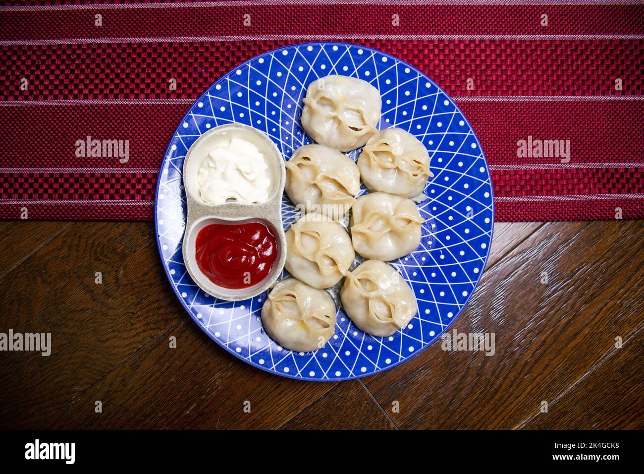 manti und Sauce auf einem blauen Teller Draufsicht Stockfoto