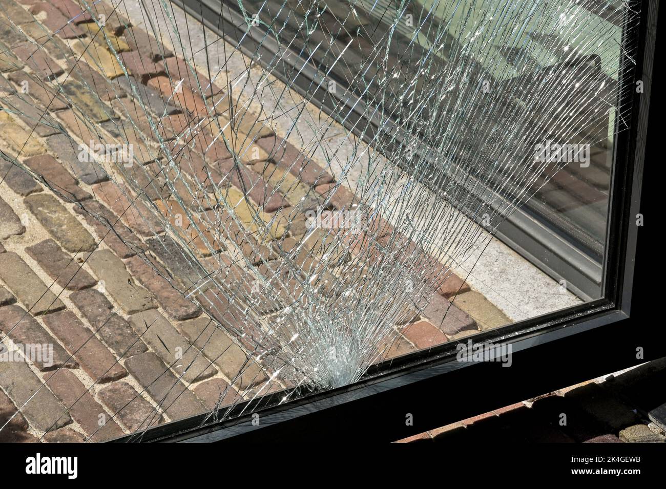 Nahaufnahme von Rissen in einer Scheibe aus gehärtetem Glas in einer Tür, nachdem sie von einem Gegenstand getroffen wurden. Keine Personen. Stockfoto