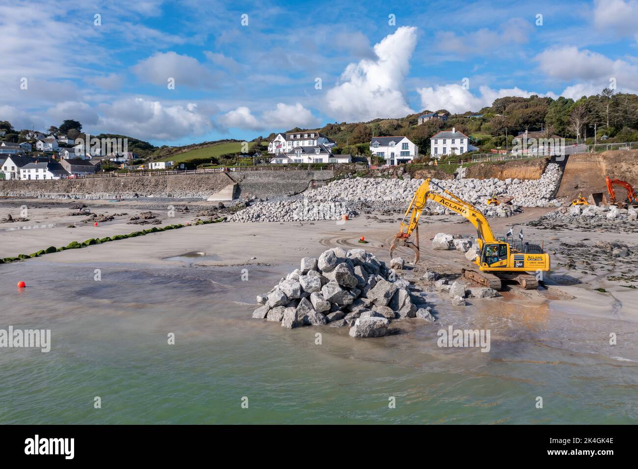 COVERACK, CORNWALL, GROSSBRITANNIEN - 23. SEPTEMBER 2022. Mechanische Bagger auf einer Baustelle, die Küstenverteidigungen und Meeresmauern mit Felsen aus einem quarr reparieren Stockfoto