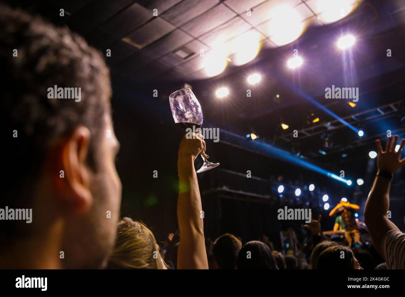 Goiânia, Goias, Brasilien – 25. September 2022: Fokus auf Glas mit Getränk in der Hand der Person hinterleuchtet in Theatershow mit blauem Licht. Stockfoto