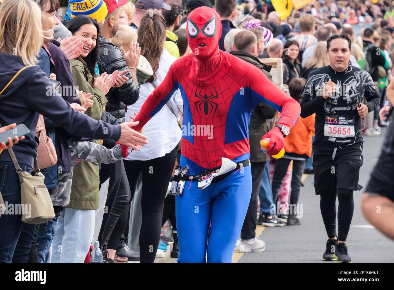 London, 2.. Oktober 2022. Mehr als 40.000 Teilnehmer gehen zum London Marathon 42. auf die Straßen der Hauptstadt. Die Veranstaltung, die Eliteläufer und Rollstuhlfahrer anzieht, bringt auch Millionen Pfund für wohltätige Zwecke durch die Teilnahme von Club- und Fitnessläufern zusammen mit denen, die nur die 26 Meilen Herausforderung annehmen wollen. Ein Läufer im Spiderman Kostüm wird von der Menge am Straßenrand begrüßt. Stockfoto