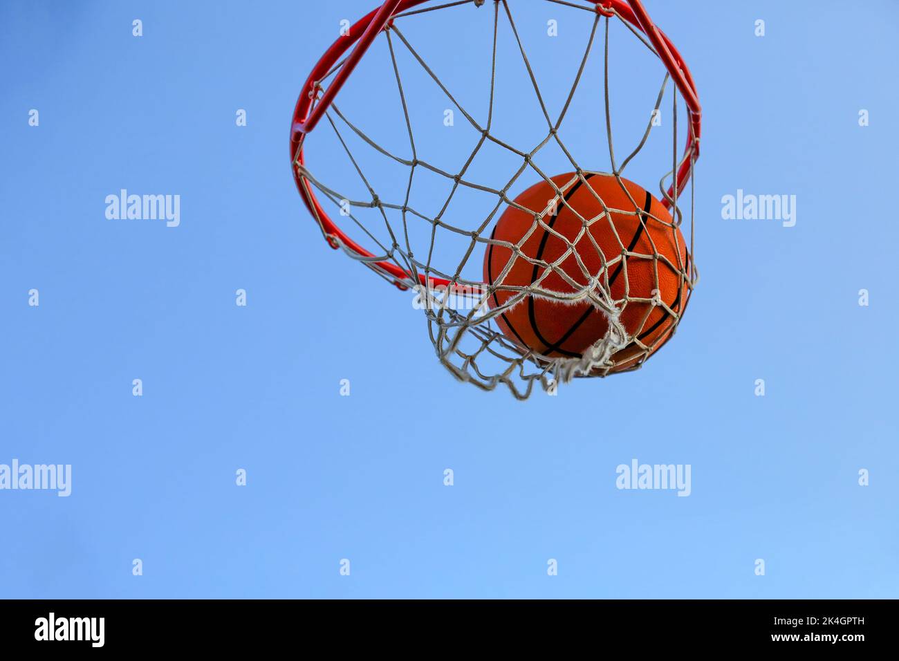 Ein Basketball im Netz gegen den Himmel. Sport, Straßenspiel. Der Ball