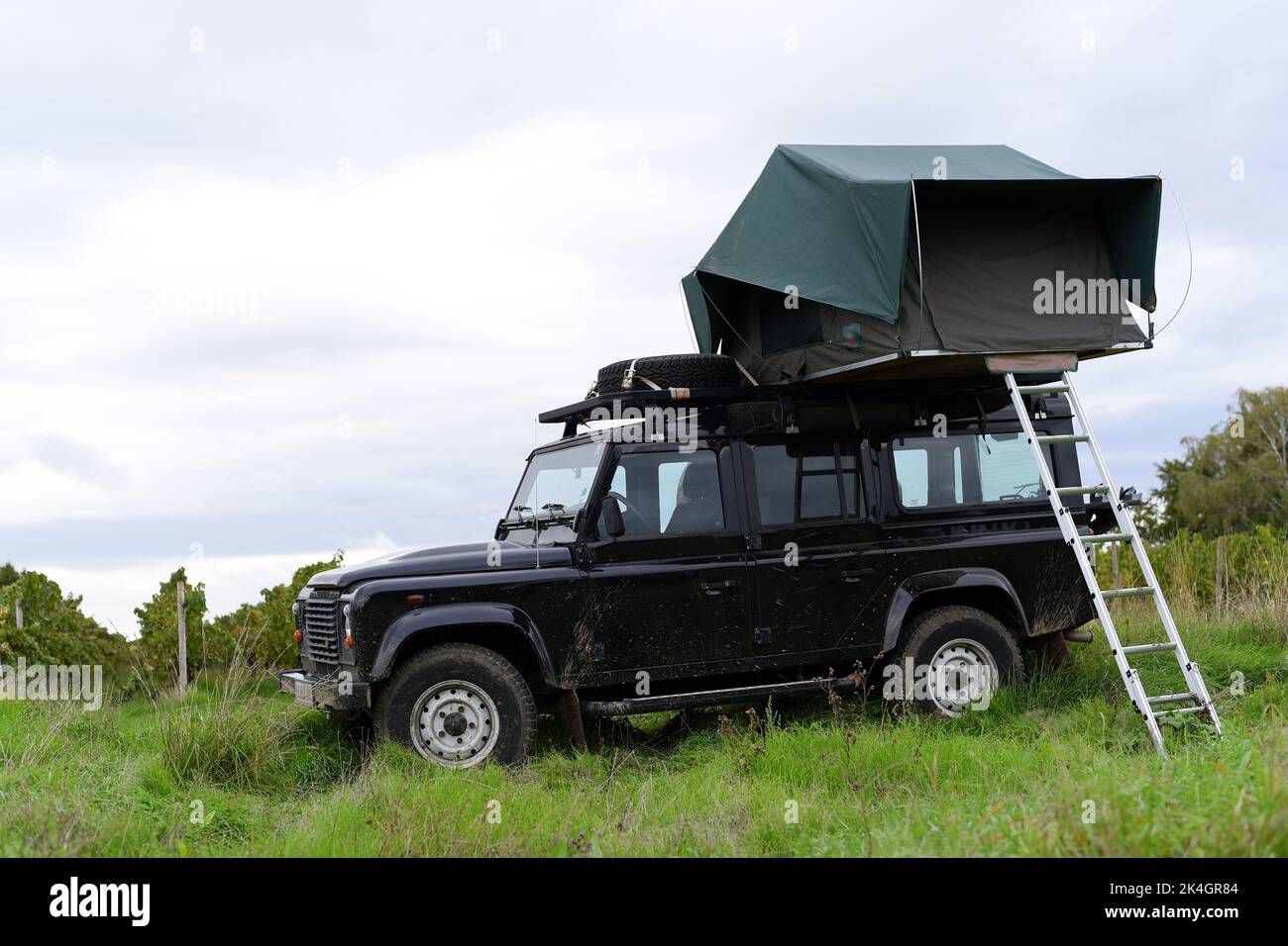 Offroad-Van auf einem Feld mit Zelt auf dem Dach geparkt. Stockfoto
