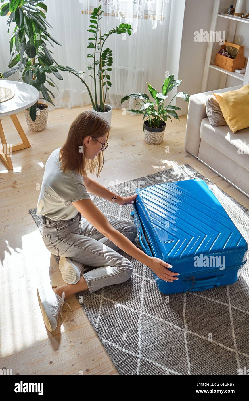 Eine junge Frau packt Koffer, sie ist gezwungen, ihr Haus zu verlassen. Zwangsumsiedlung, Flucht aus dem Land, geschlossene Grenzen Stockfoto