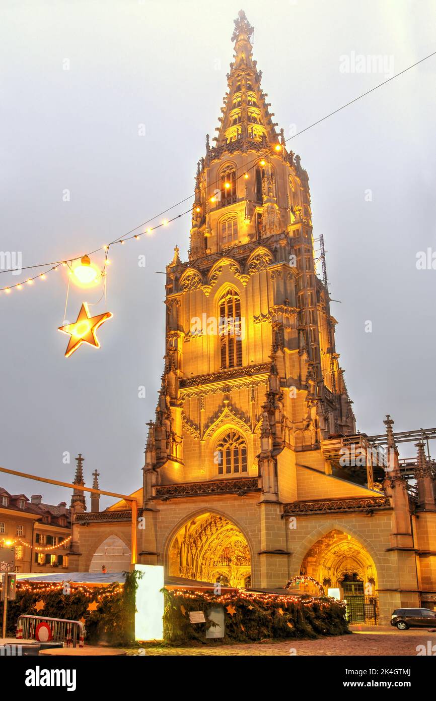 Nachtszene des Berner Münster (Schweizerisch-reformierte Kathedrale) in einer Winternacht, die über dem Berner Weihnachtsmarkt in der Schweiz thront. Stockfoto