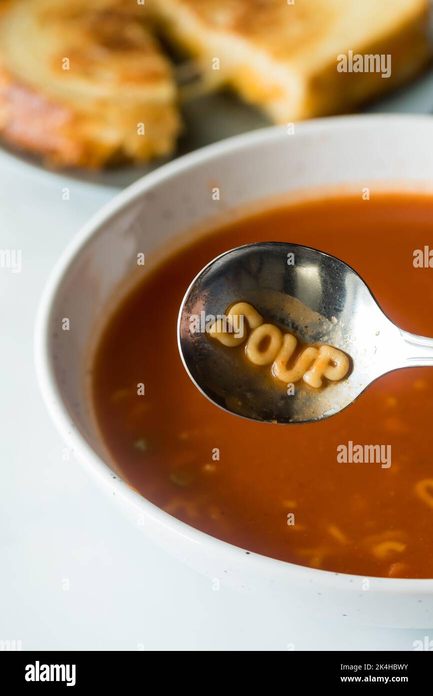 Eine Schüssel gefüllt mit Alphabet Tomatensuppe und das Wort Suppe im Löffel. Stockfoto