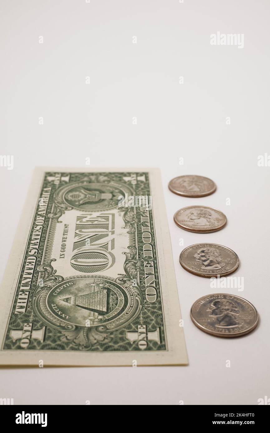 US-Dollar-Schein neben vier 25-Cent-Münzen. Stockfoto